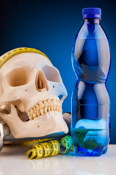 Human skull and fitness dumbbells and bottle of water — Stock Photo, Image