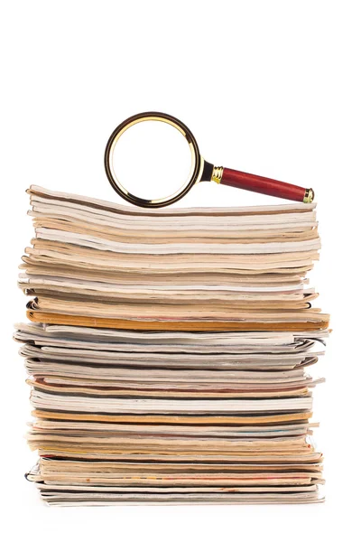 Pile of newspapers and magnifying glass — Stock Photo, Image