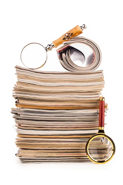 Pile of newspapers and magnifying glass — Stock Photo, Image
