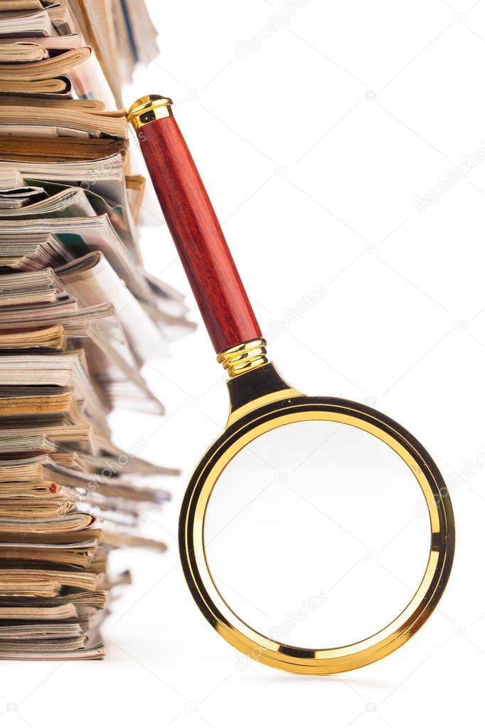 pile of newspapers and magnifying glass
