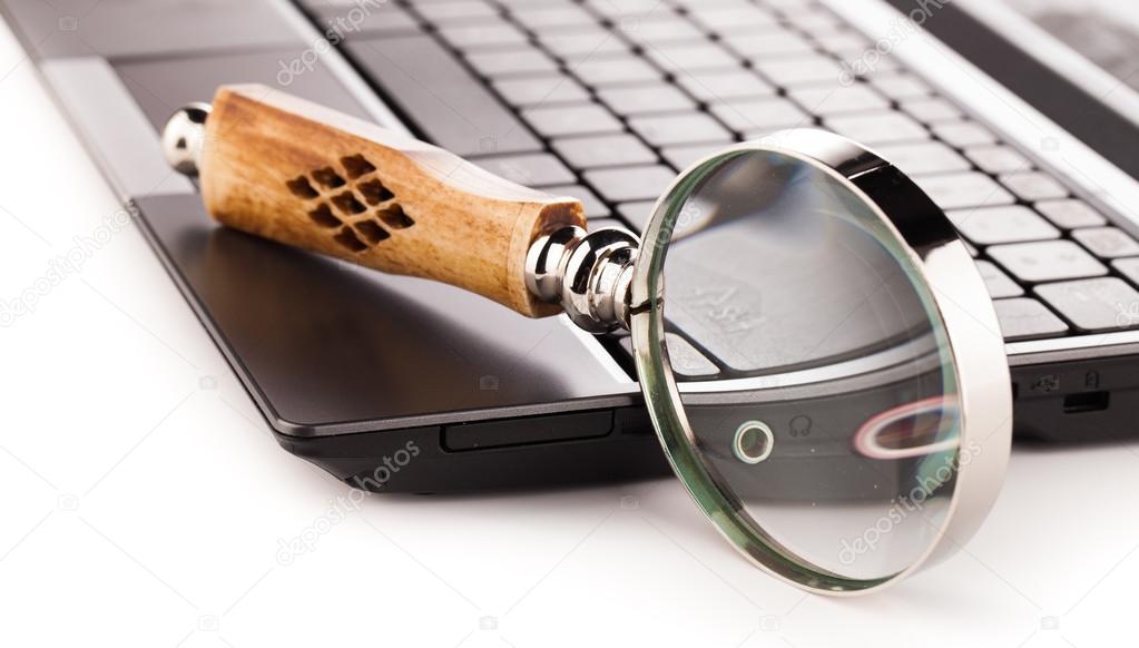 laptop computer keyboard and magnifying glass