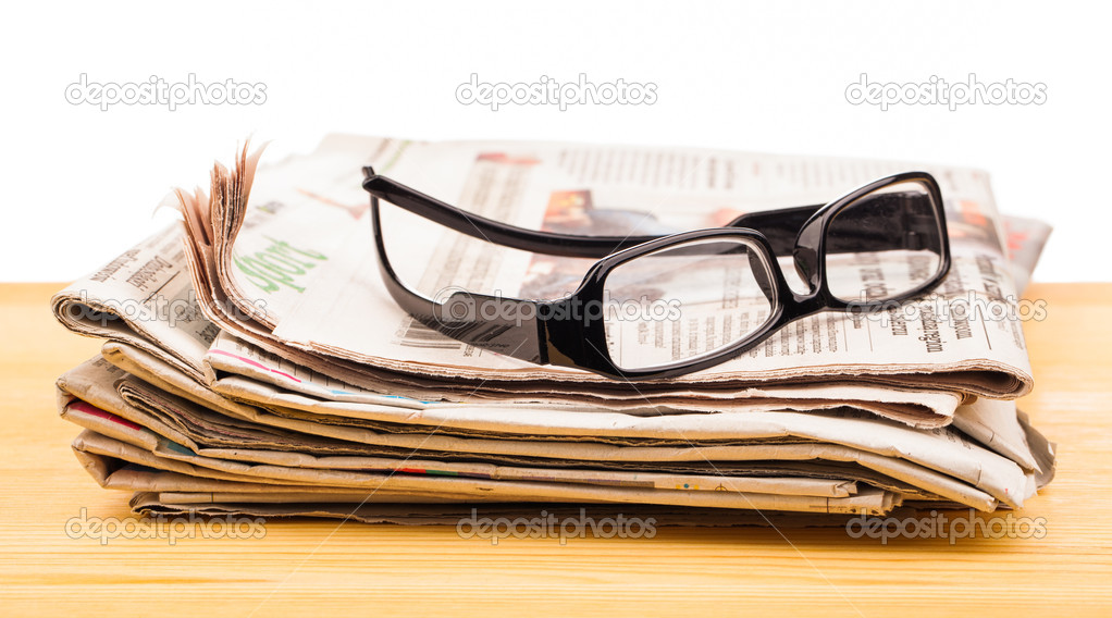 Pile of newspapers and reading glasses