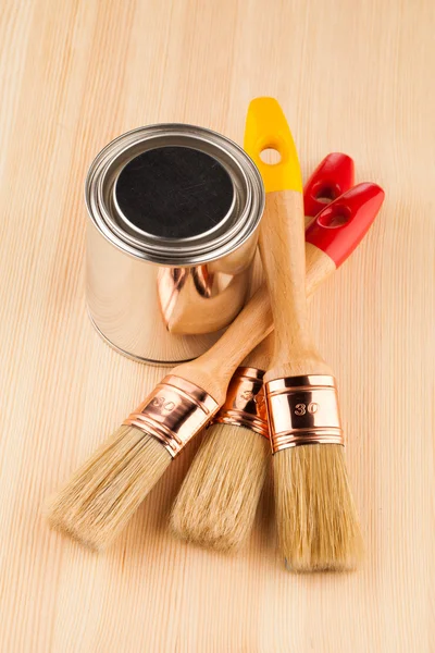 Can of paint with paintbrushes on wooden table — Stock Photo, Image
