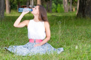 genç kadın su şişesinden içiyor.