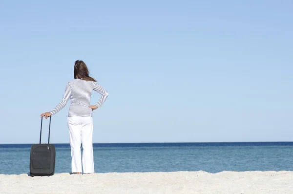 Mujer soltera esperando con equipaje en la playa — Foto de Stock