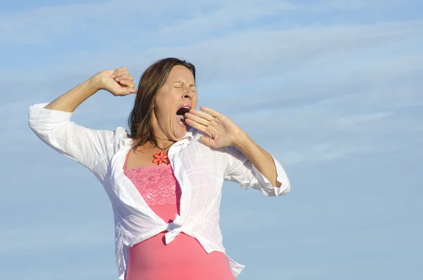 Mujer cansada bostezando fondo del cielo — Foto de Stock