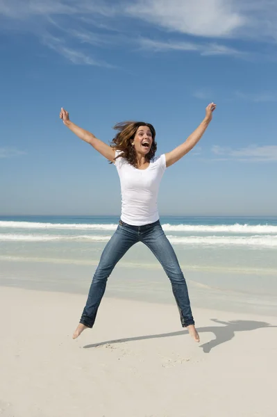 Jonge vrouw te springen van vreugde op strand — Stockfoto