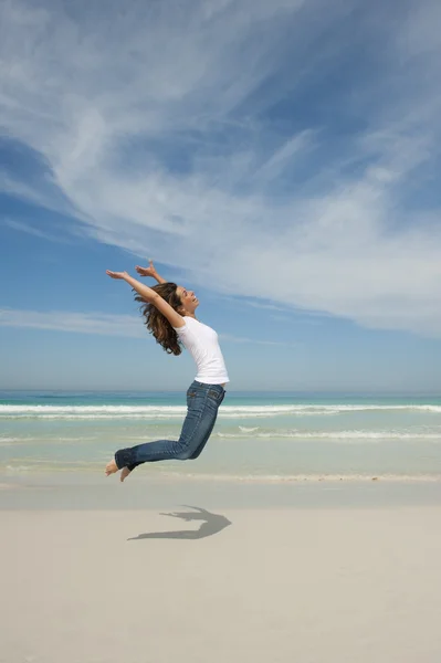 Щаслива жінка стрибає з радістю на пляжі — стокове фото