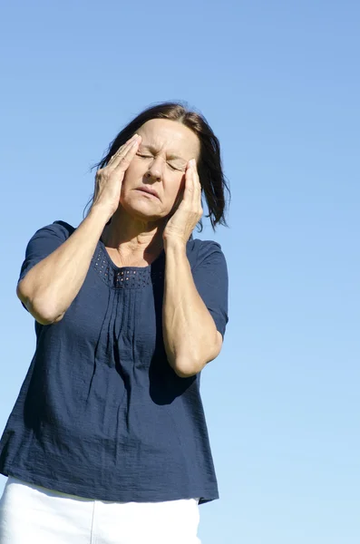 Stressed mature woman headache blue background — Stock Photo, Image