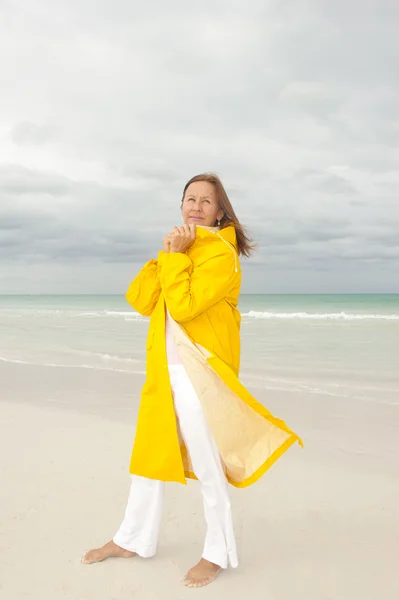 Vrouw regenjas herfstweer op strand — Stockfoto