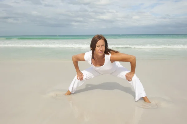 Volwassen vrouw uitoefening strand — Stockfoto