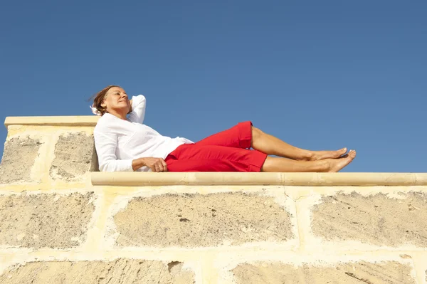 Gelukkig volwassen vrouw liggend op de muur — Stockfoto