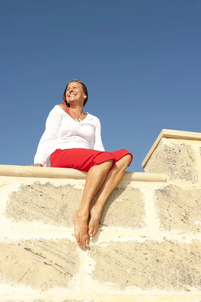 Glücklich reife Frau sitzt auf Wand — Stockfoto