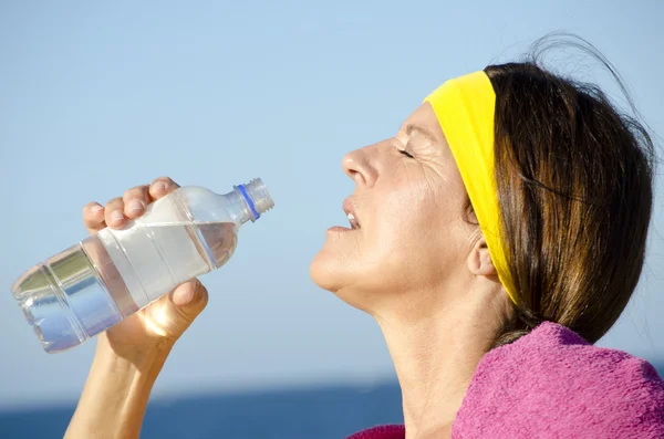 Exercising mature woman drinking water ocean — Stock Photo, Image