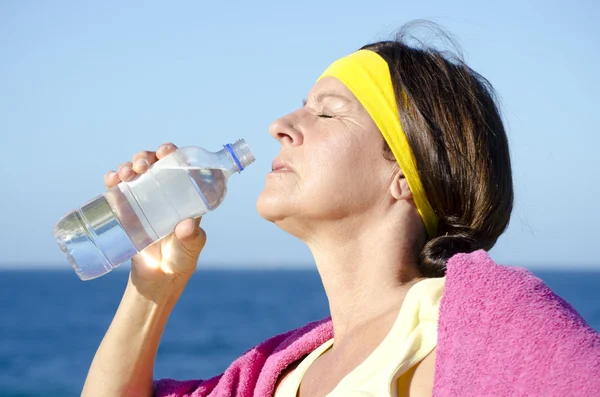 Exercising mature woman drinking water outdoor — Stock Photo, Image