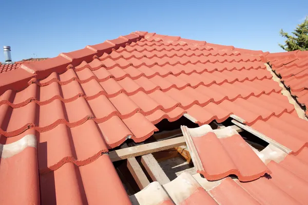 Beschadigde rode tegel dak bouw huis Stockfoto