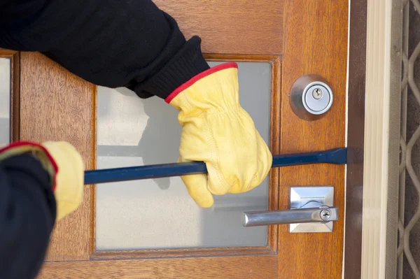 Inbreker breken in huis met breekijzer op deur — Stockfoto