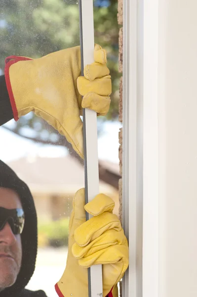 Burglar breaking through window of home — Stock Photo, Image