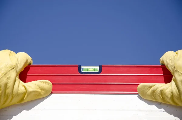 Hands with gloves on spirit level outdoor construction — Stock Photo, Image