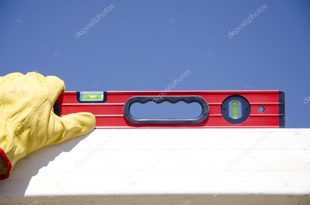 Hands with gloves on spirit level outdoor construction