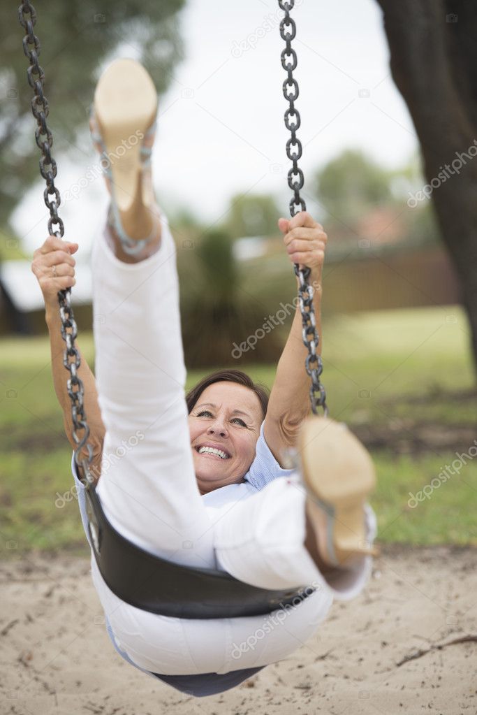 Happy relaxed mature woman on swing outdoor