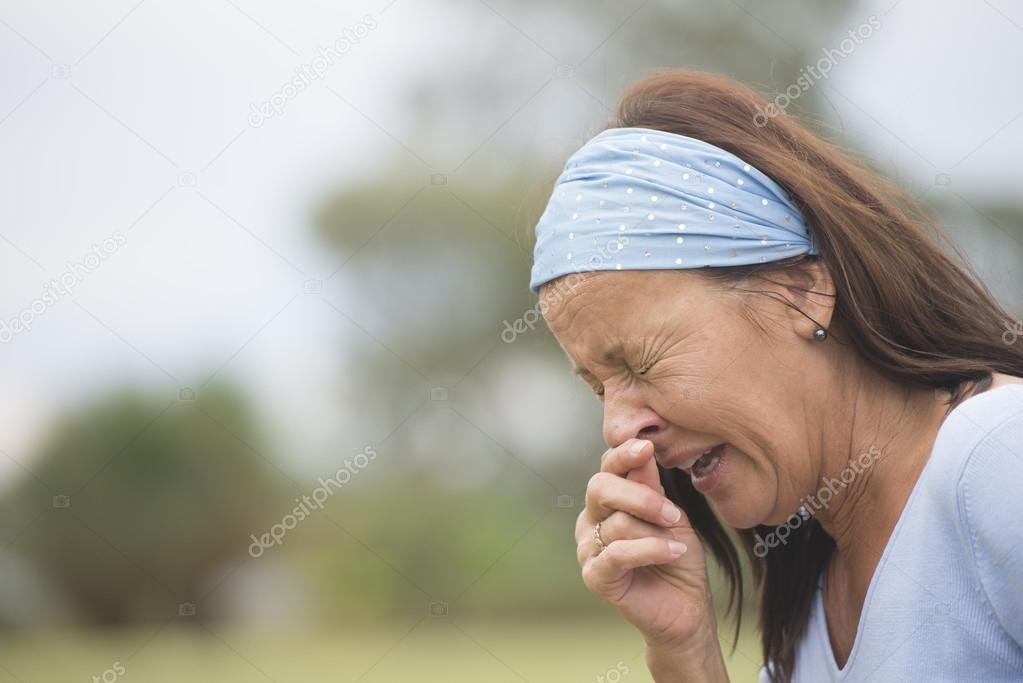 Sneezing woman with flu, hayfever or cold outdoor