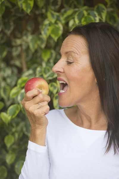 Felice donna matura mangiare mela rossa — Foto Stock