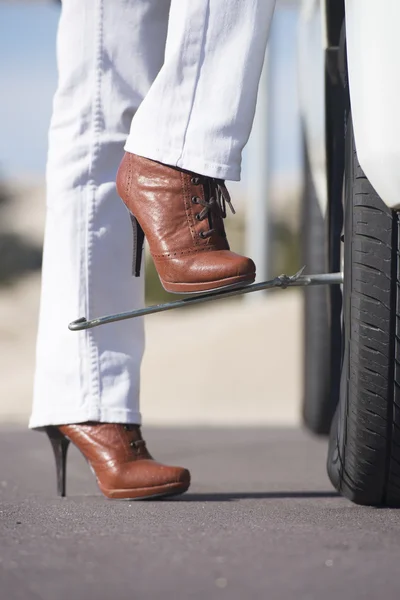 Kvinna däck förändring bil bryta ner remote street — Stockfoto