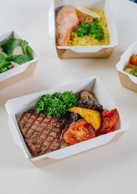 Konteynırlarda yemek. Düzgün beslenme, günlük diyet, kilo kaybı. İçecek, ızgara sebzeli dana biftek kuskus soslu somon bifteği. Üst görünüm