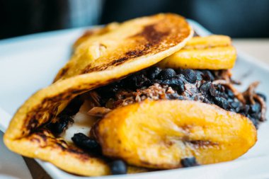 Domuz derisi ve taze peynirle doldurulmuş kızarmış mısır hamurundan Venezuela cachapası. Makro seçici odaklanma.