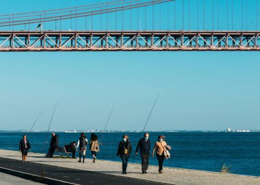 Lisbon, Portugal - January 7, 2022: Fishermen on a river Tagus near the 25 April bridge in Lisbon