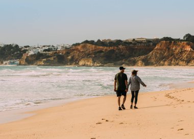 Falesia Beach, Algarve, Portekiz - 29 Ocak 2022: Arka planda Albufeira ile Portekiz 'in Algarve kentindeki Falesia Sahili' nde yürüyen yaşlı çift