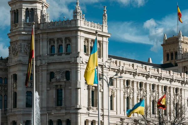 The flag of Spain and Ukraine flutter in the wind in front of Cibeles in Madrid, Spain. European Union and Spanish solidarity concept as Russia invaded Ukraine in February 2022