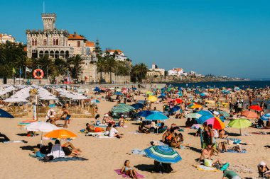 Estoril, Portugal - August 2, 2022: Crowded sandy Tamariz beach in Estoril near Lisbon, Portugal during the summer