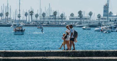 Cascais, Portugal - August 28, 2022: Family walk on pier in Cascais, Portugal with bay and boats on the background