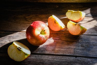 Elmalar pişirilir, bir güneş ışınının vurduğu ahşap mutfak masasında dilimlenir..