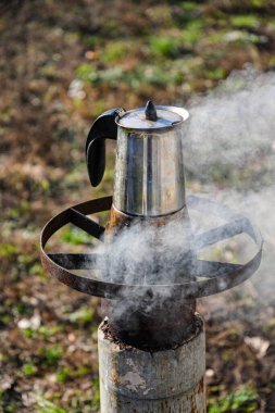 Bahçede, odun yakan bir ocakta gayzer kahve makinesinde kahve yapmak. Güzel bir sonbahar günü.