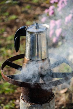 Bahçede, odun yakan bir ocakta gayzer kahve makinesinde kahve yapmak. Güzel bir sonbahar günü.