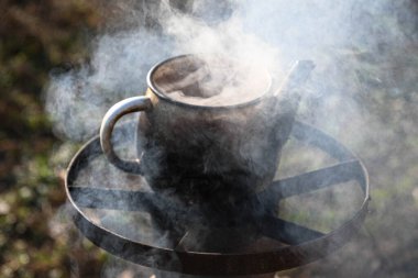 Dışarıdaki bir su ısıtıcısında, yanan bir odun sobasında. Zor zamanlar, nasıl hayatta kalınacağı. Açık hava yemekleri..