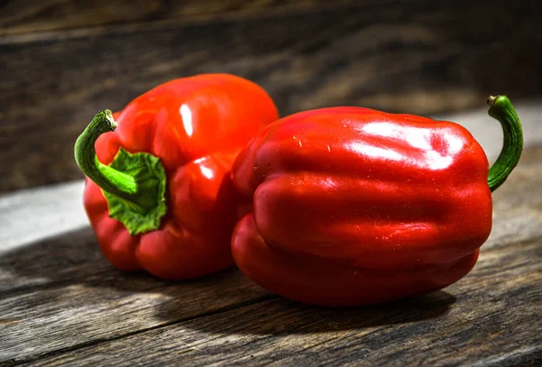 Two Red Bell Peppers Lie Wooden Table lizenzfreie Stockbilder