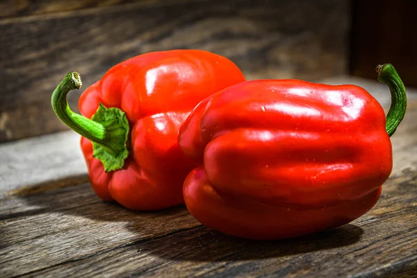 Two Red Bell Peppers Lie Wooden Table lizenzfreie Stockfotos