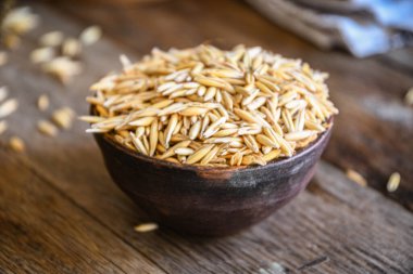 On the wooden kitchen table are a ceramic bowl of oat grains, a glass cup with oat kvass on a kitchen napkin, and an earthen jug. Village life.