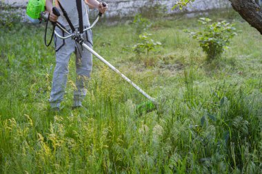 Adam çim biçiyor, kesiyor, fazla büyümüş bir bahçede çim biçiyor bahçe biçme makinesi ya da moto-tırpan kesiyor. Bahçe temizliği, bahçe temizliği. Umurumuzda değil....