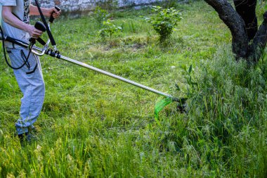 Adam çim biçiyor, kesiyor, fazla büyümüş bir bahçede çim biçiyor bahçe biçme makinesi ya da moto-tırpan kesiyor. Bahçe temizliği, bahçe temizliği. Umurumuzda değil....