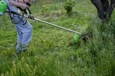 Adam çim biçiyor, kesiyor, fazla büyümüş bir bahçede çim biçiyor bahçe biçme makinesi ya da moto-tırpan kesiyor. Bahçe temizliği, bahçe temizliği. Umurumuzda değil....
