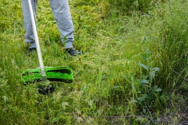 Adam çim biçiyor, kesiyor, fazla büyümüş bir bahçede çim biçiyor bahçe biçme makinesi ya da moto-tırpan kesiyor. Bahçe temizliği, bahçe temizliği. Umurumuzda değil....