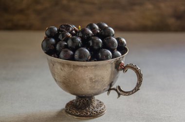 Masanın üzerinde kuşüzümü hasadı olan gümüş bardak..