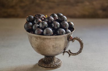 Masanın üzerinde kuşüzümü hasadı olan gümüş bardak..