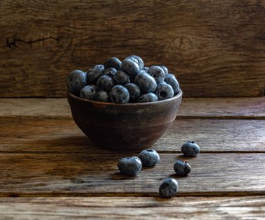 Blueberries in a clay cup, on a wooden table. Ripe berries in the kitchen, harvest.