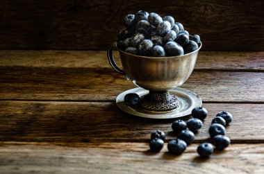 Blueberries in a silver cup, on a wooden table. Ripe berries in the kitchen, harvest.